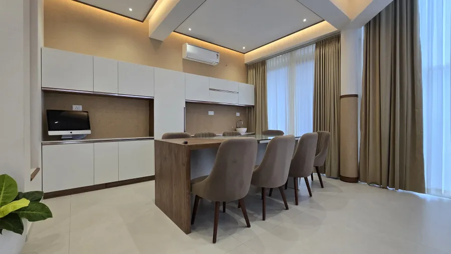 Long work table and kitchenette beneath cove lighting